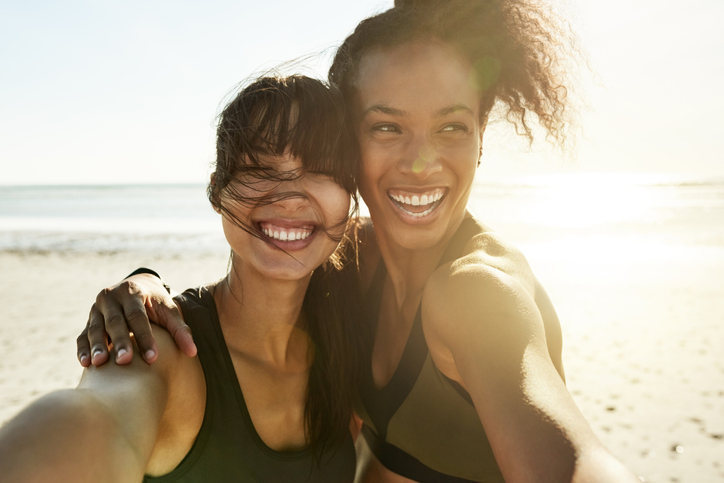 Cropped portrait of two attractive and athletic young women taking selfies while out for a run on the beach