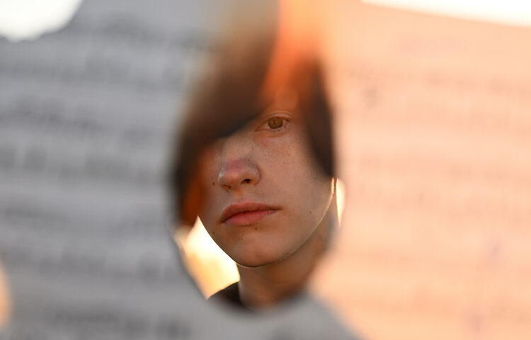 teenager looking through a hole from a burned paper